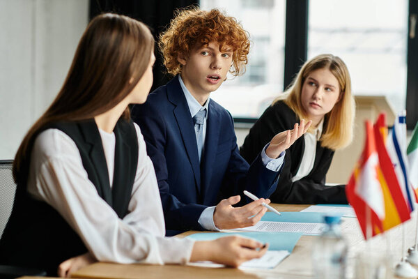 Трое подростков участвуют в оживленной дискуссии во время Модельной конференции ООН.