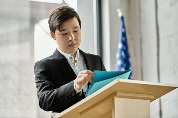 Подросток в костюме просматривает свои заметки на подиуме.