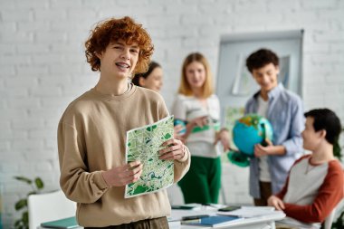 Teenage boy holds a map while participating in a UN Model conference. clipart