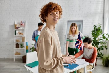 Genç çocuk BM Model simülasyonunda diğer katılımcılarla çevrili bir İngiliz bayrağı tutuyor..