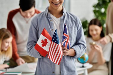 Teen holds flags for Canada, US, UK in UN Model. clipart