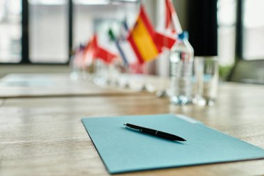 Bir BM Model konferansında bir sonraki müzakere turunu bekleyen bir kalem mavi klasörün üzerinde duruyor.