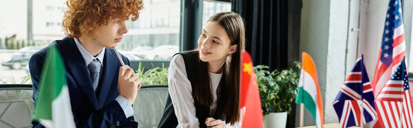 Two teenagers participate in a UN model, surrounded by flags representing various nations.