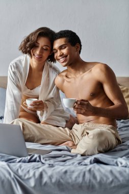 A young couple enjoys their morning coffee together in bed. clipart