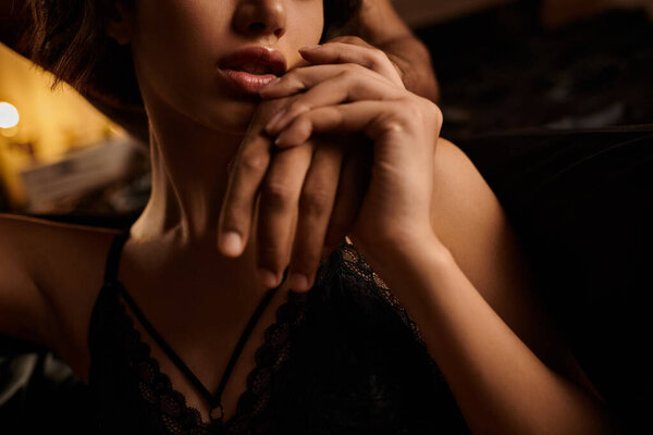 Крупный план пары, обнимающейся на кровати. Женская рука нежно держится за руки мужчин.