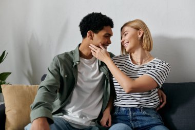 Genç, çok kültürlü bir çift modern bir dairede bir kanepede oturur, hassas bir yakınlık ve şefkat anlarını paylaşırlar..