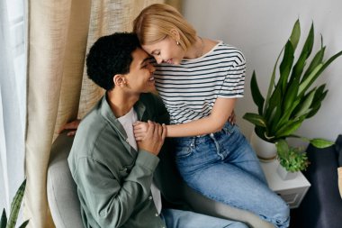 Genç, çok kültürlü bir çift modern evlerindeki bir kanepede birlikte oturur ve hassas bir anı paylaşırlar..