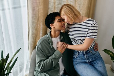 Genç, çok kültürlü bir çift büyük pencereleri ve yumuşak ışıklandırması olan modern bir dairede derinden bağlı bir şekilde oturuyor..