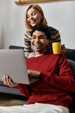 Mutlu, çok kültürlü bir çift modern dairelerinde birlikte vakit geçirir. Laptop kullanırken gülerler..