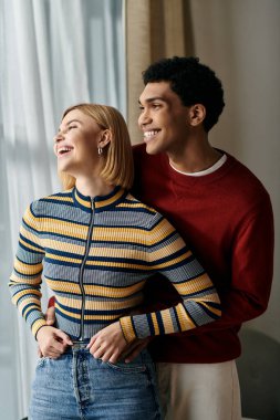 Gündelik giyinmiş çok kültürlü bir çift modern bir dairede birbirlerine eşlik etmekten hoşlanırlar..