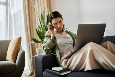 Bir kadın dizüstü bilgisayarla kanepede oturuyor, evden çalışıyor..