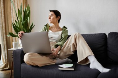 Evindeki koltukta oturan bir kadın dizüstü bilgisayarla çalışıyor..