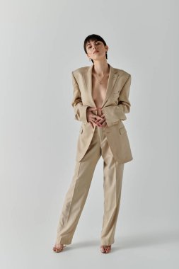 Bronz takım elbiseli bir kadın stüdyo ortamında güven içinde poz veriyor..