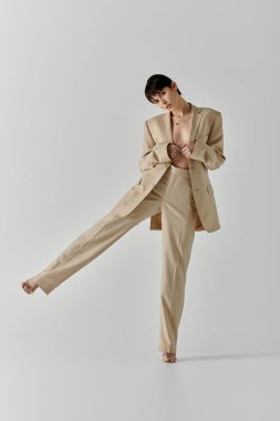 A woman in a tan suit poses with one leg extended forward, standing on a white background. clipart