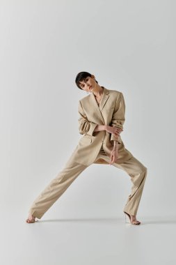 Bej takım elbiseli kadın kendine güvenen poz veriyor. Bacağı açık, güç saçıyor..