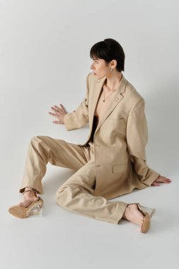 Bir kadın bronz bir takım elbiseyle poz verir, gözlerini yana çevirir..