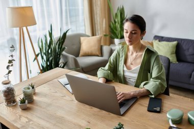 Ev masasında dizüstü bilgisayarında çalışan bir kadın..