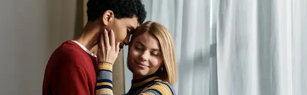 stock image A happy interracial couple share a tender moment in a modern apartment, showcasing the beauty of diversity and love.