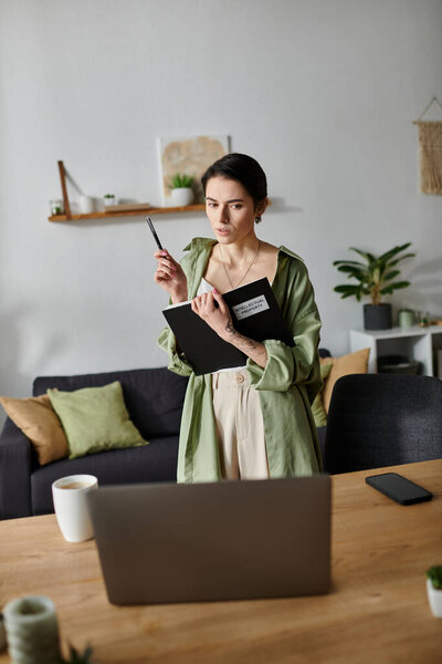 A woman stands in a home office, holding a notebook and a pencil, ready to present.