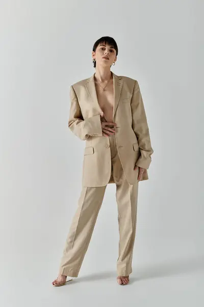 stock image A woman wearing a beige suit and heels poses for a portrait.