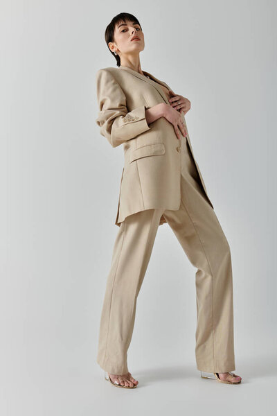 A woman wearing a light brown suit poses with a confident expression.