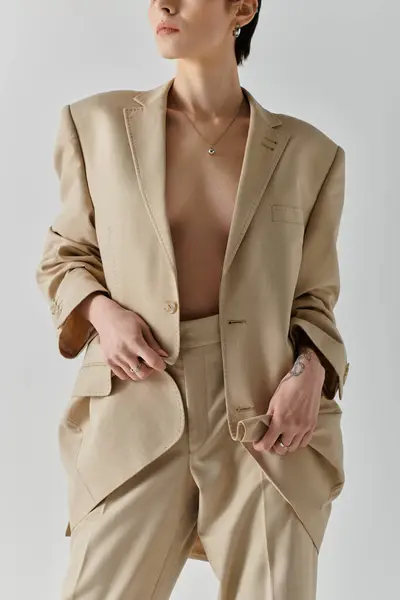 stock image A woman wears a tan suit with a relaxed, casual pose.