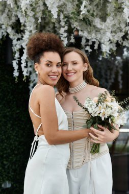 Sevgi dolu bir lezbiyen çift düğün günlerinde sarılır, güzel beyaz çiçeklerle çevrili..