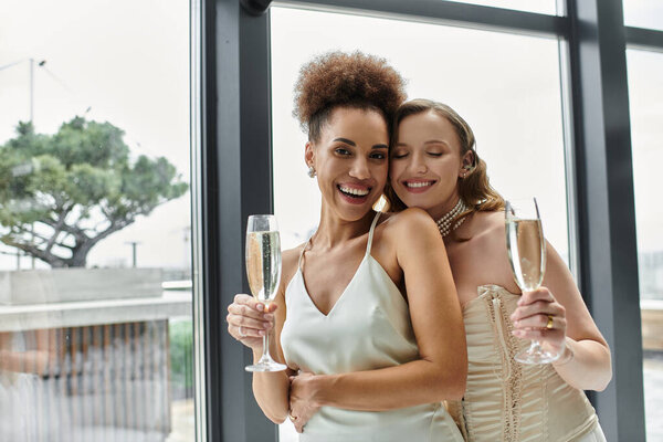 Two women, newly married, raise a glass of champagne in celebration.