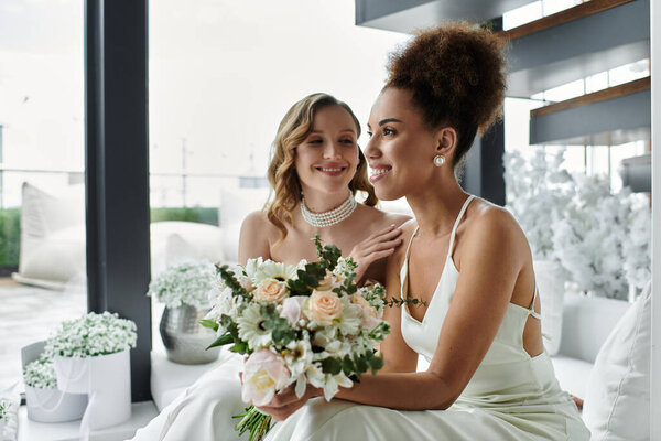 A lesbian couple smiles at each other on their wedding day.
