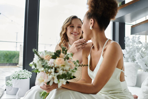 Two brides share a loving moment on their wedding day.