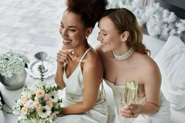 A lesbian couple celebrates their wedding day with smiles and champagne.