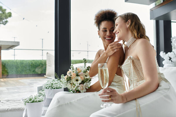 Лесбиянки поднимают тосты за день своей свадьбы, улыбаются и держат флейту с шампанским.