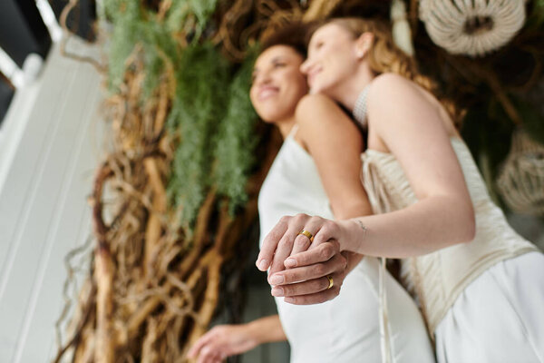 A lesbian couple smiles and holds hands during their wedding ceremony.