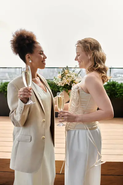 stock image A lesbian couple celebrates their wedding with a glass of champagne on a rooftop terrace.