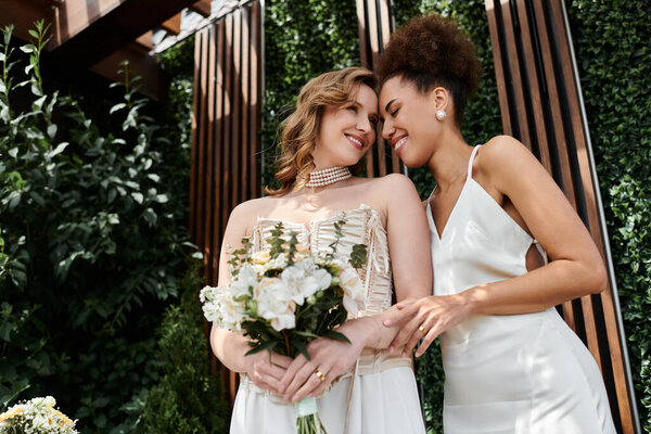 Две невесты улыбаются друг другу, держа букет цветов, в день их свадьбы.
