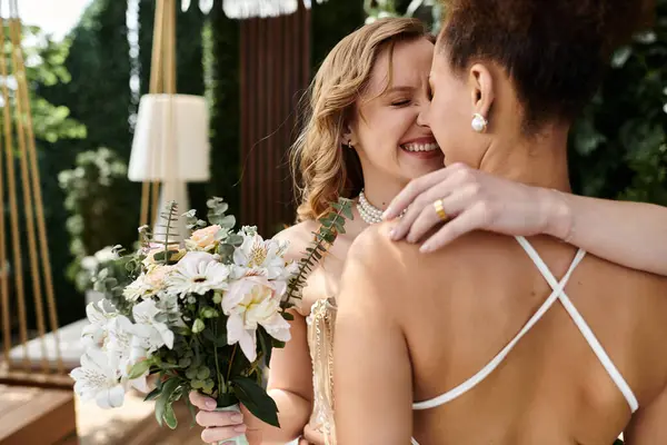 stock image A lesbian couple shares a tender embrace on their wedding day, surrounded by lush greenery.