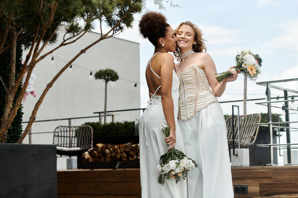 Two brides, one dark-skinned and the other light, share a kiss on their big day.
