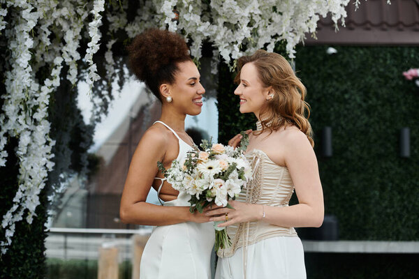 Two brides look at each other lovingly during their wedding ceremony.