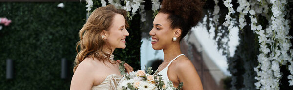 Two brides exchange smiles during their wedding ceremony.