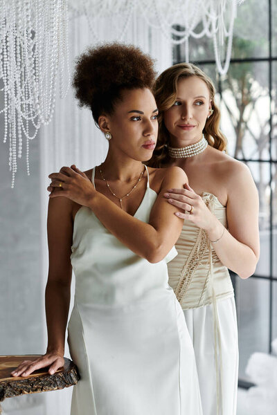 Две невесты в белых платьях, держащие друг друга близко, в день своей свадьбы.