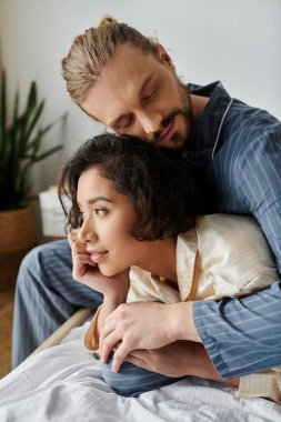 A man and woman in pajamas cuddle and relax in bed together. clipart