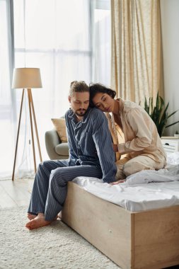 Bir çift, parlak bir yatak odasında, bir yatakta rahatlar, bir anlık yakınlığın tadını çıkarırlar..