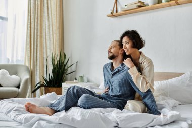 Pijamalı, sevgi dolu bir çift rahat bir yatak odasında yatakta dinleniyor..