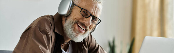 A mature gay man with tattoos and grey hair works remotely from home, showcasing a modern lifestyle and LGBTQ+ inclusion.