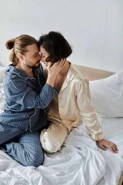 stock image Couple in pajamas sharing a loving moment, foreheads touching in deep connection.