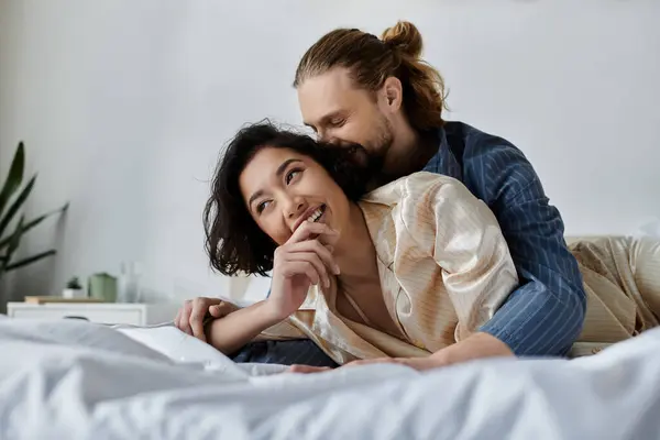 stock image A couple cuddles on a bed, laughing and enjoying each others company.