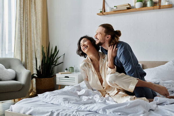 A loving couple shares a laugh and a hug on their bed, enjoying a relaxing moment together.