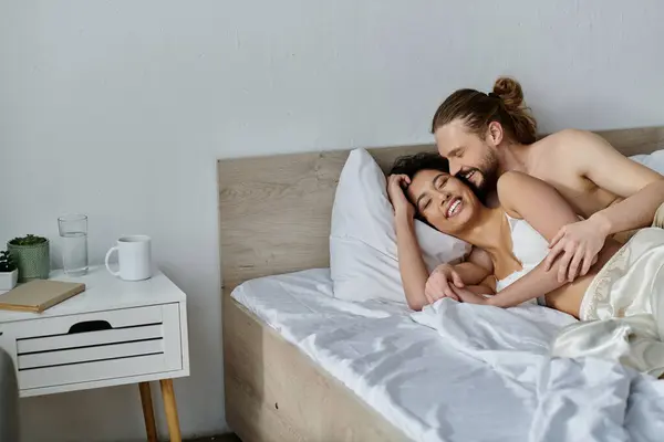 stock image A loving couple embraces in bed, enjoying a relaxing morning together.