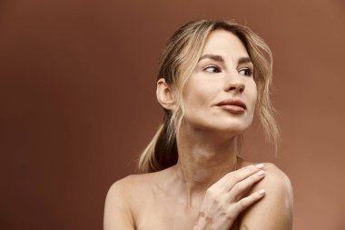 Vitiligo 'su olan genç bir kadın, omuzlarını bej bir arka plana yaslayarak rahatça poz veriyor..