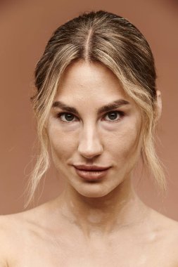Vitiligo 'lu genç bir kadının portresi, omuzları bej arka planda çıplak poz veriyor..